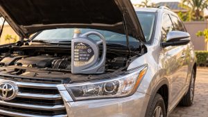 A 5-litre bottle of Everest Full Synthetic 0W-20 motor oil resting on the open engine bay of a silver Toyota Highlander